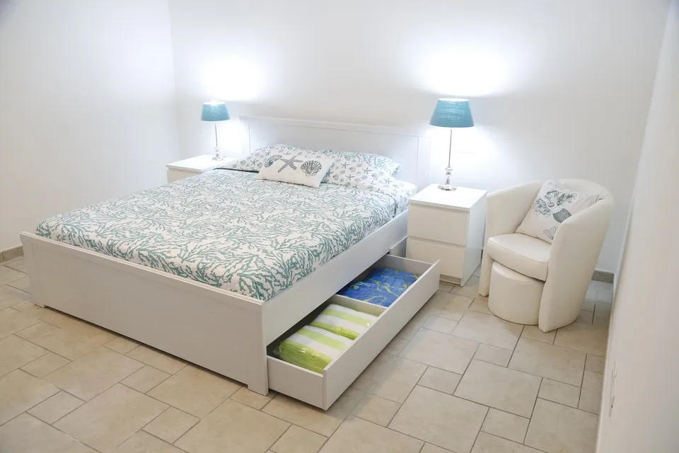 Master bedroom storage with folded linens in the drawers beneath the bed