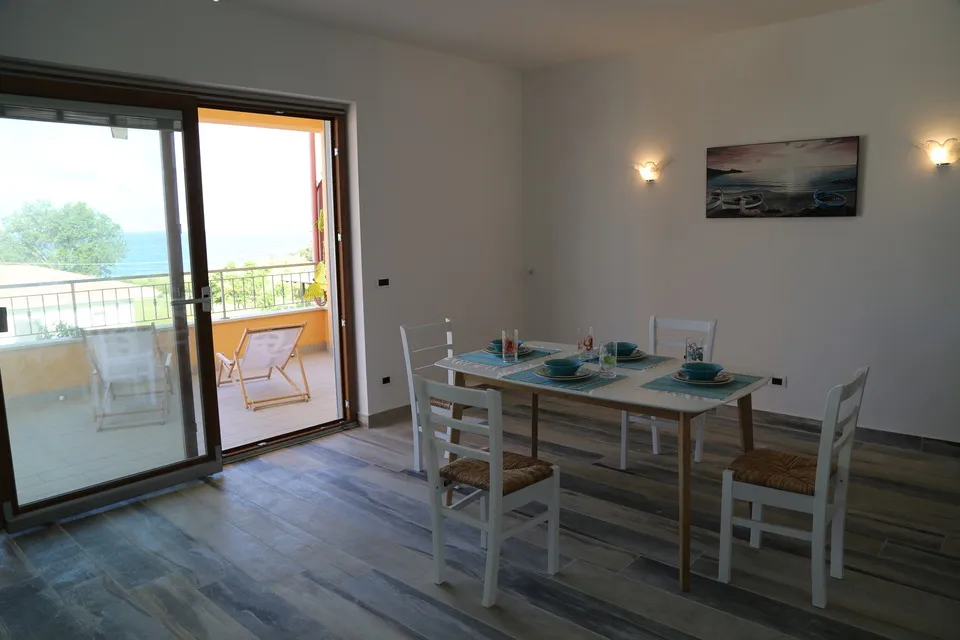 Kitchen table with the balcony door open to the sea