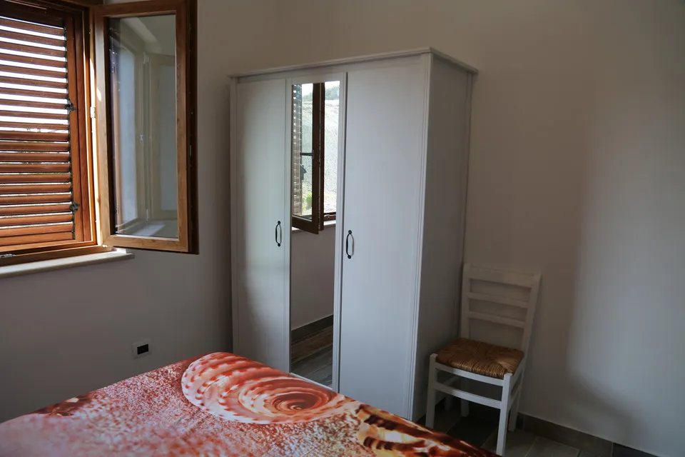 Second bedroom armoire, chair, and window